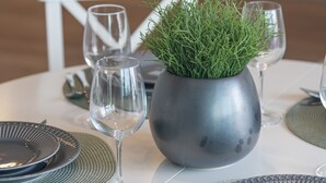 Une table à manger dressée avec des assiettes, des couverts et une plante en pot.