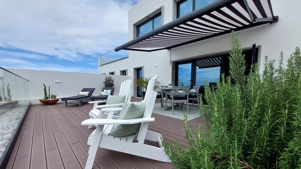 Une terrasse extérieure moderne avec des chaises longues blanches, une table à manger et des plantes en pot.