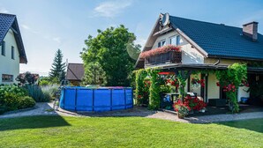 A house with a blue pool, a covered patio with red flowers, and a well-maintained lawn. - 2 bedroom amazing home in Ploskinia (Ploskinia)