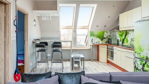 A compact kitchen with a dining area, a loft bedroom with a skylight, and a living room with a sofa. - 2 bedroom amazing home in Ploskinia (Ploskinia)