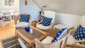 Una habitación acogedora con muebles de mimbre, techo blanco y una estantería.