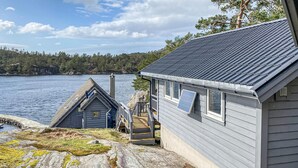 Una cabaña con un muelle que se adentra en un lago, rodeada de bosque.