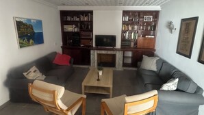 Ein Wohnzimmer mit Kamin, zwei Sofas, einem Couchtisch und Bücherregalen.