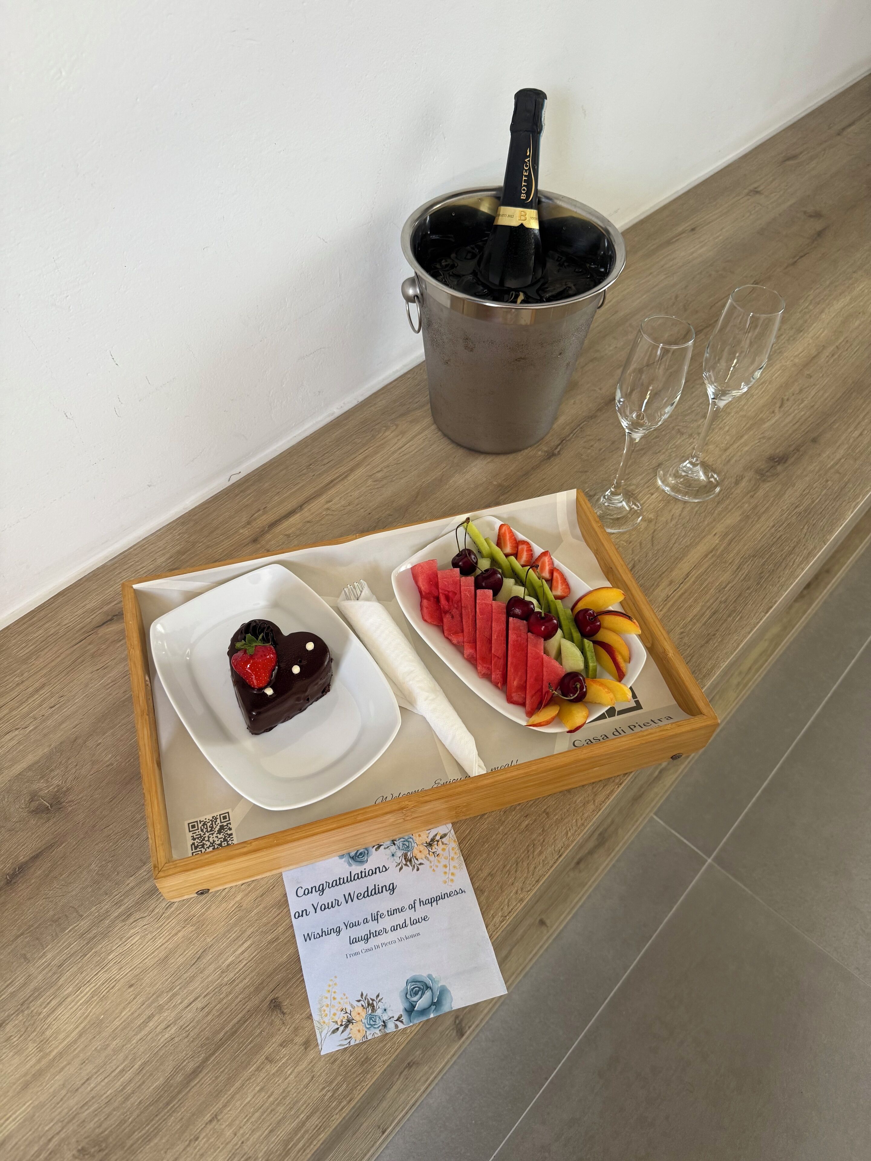 A tray with a chocolate dessert, watermelon slices, and fruit on a wooden table.