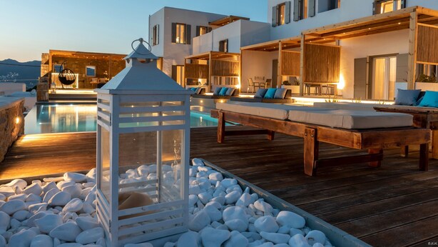 A modern outdoor pool area with lounge chairs and a glass-enclosed lantern.