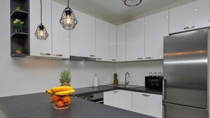 A modern kitchen with white cabinets, a stainless steel refrigerator, and a fruit bowl on the counter. - Lovely home in Zagvozd (Zagvozd)