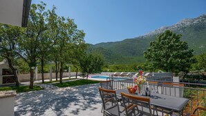 An outdoor patio with a pool, dining area, and mountain views. - Lovely home in Zagvozd (Zagvozd)
