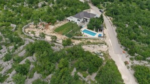 An aerial view of a house with a swimming pool, surrounded by dense greenery and a winding road. - Lovely home in Zagvozd (Zagvozd)