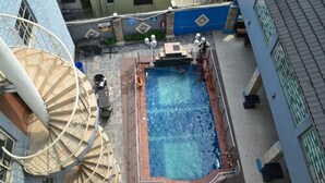 A rooftop pool surrounded by buildings with a spiral staircase and a blue wall. - Valley Front View Hotel (Lagos)