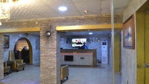 A lobby with a reception desk, seating area, and a large screen. - Valley Front View Hotel (Lagos)