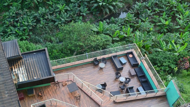 An aerial view of a rooftop deck with outdoor seating, surrounded by lush greenery. - Valley Front View Hotel (Lagos)