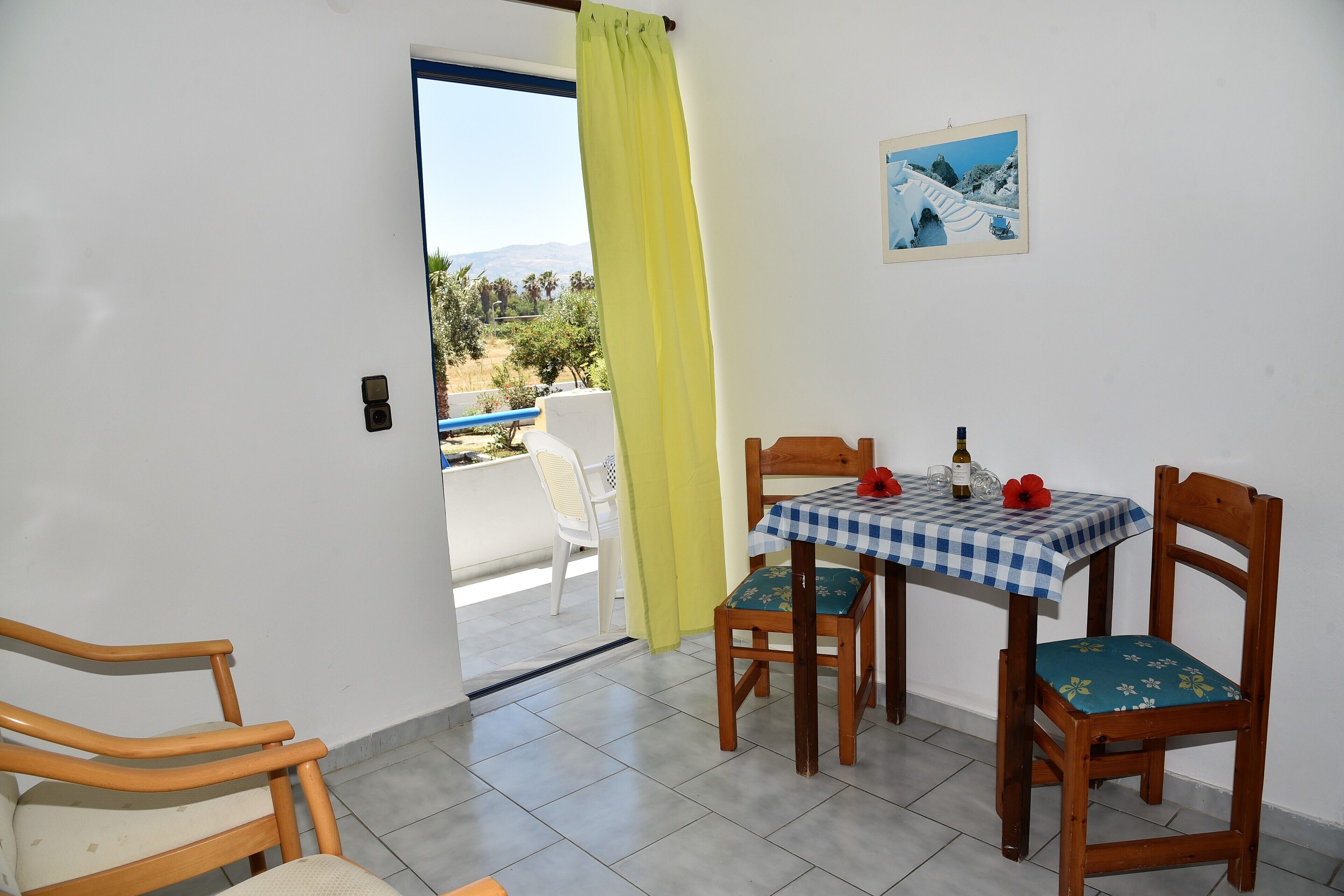Un balcón con mesa y sillas, vistas al exterior y una puerta con cortina.