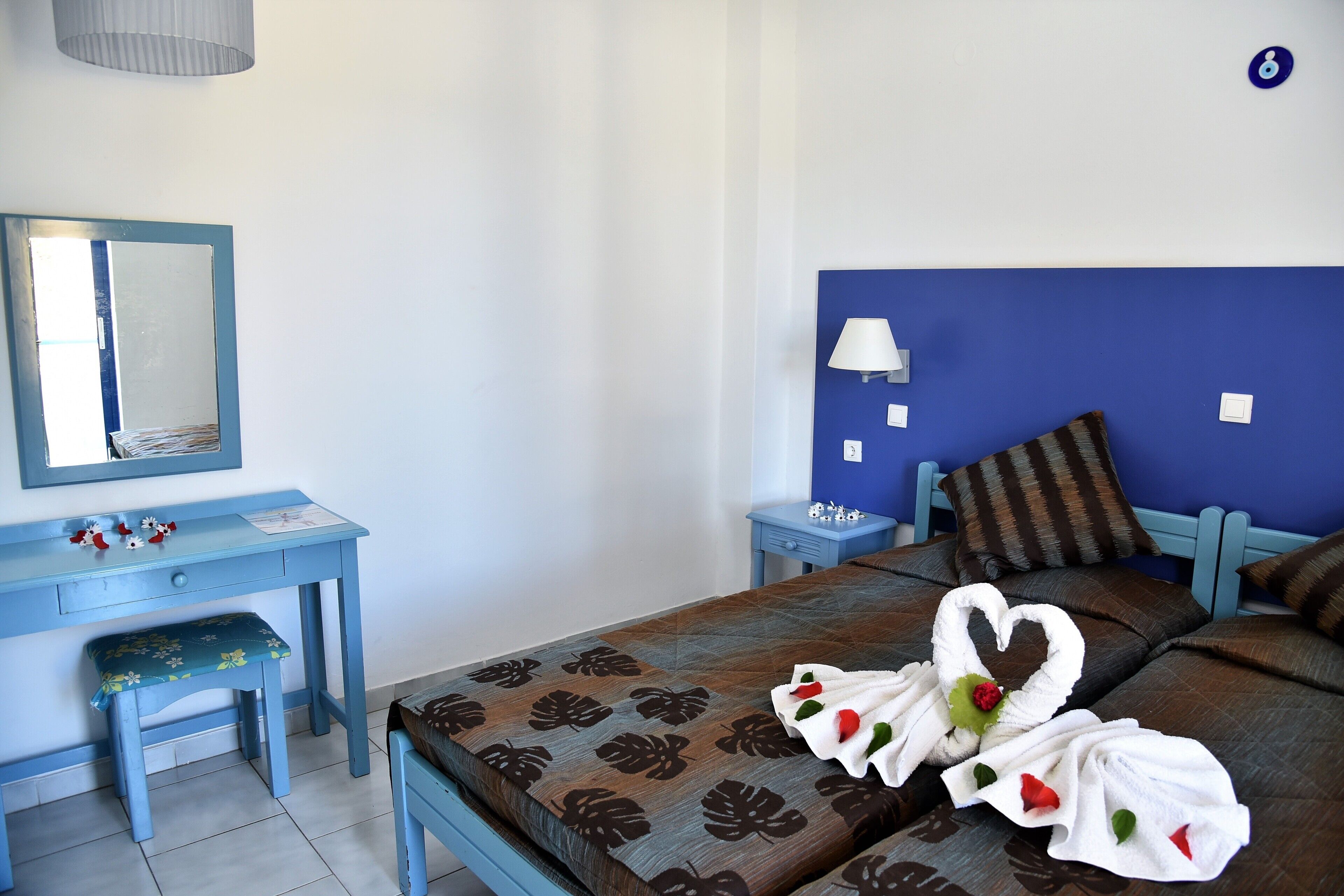 Habitación de hotel con cama, escritorio, silla, lámpara y espejo instalado en la pared.