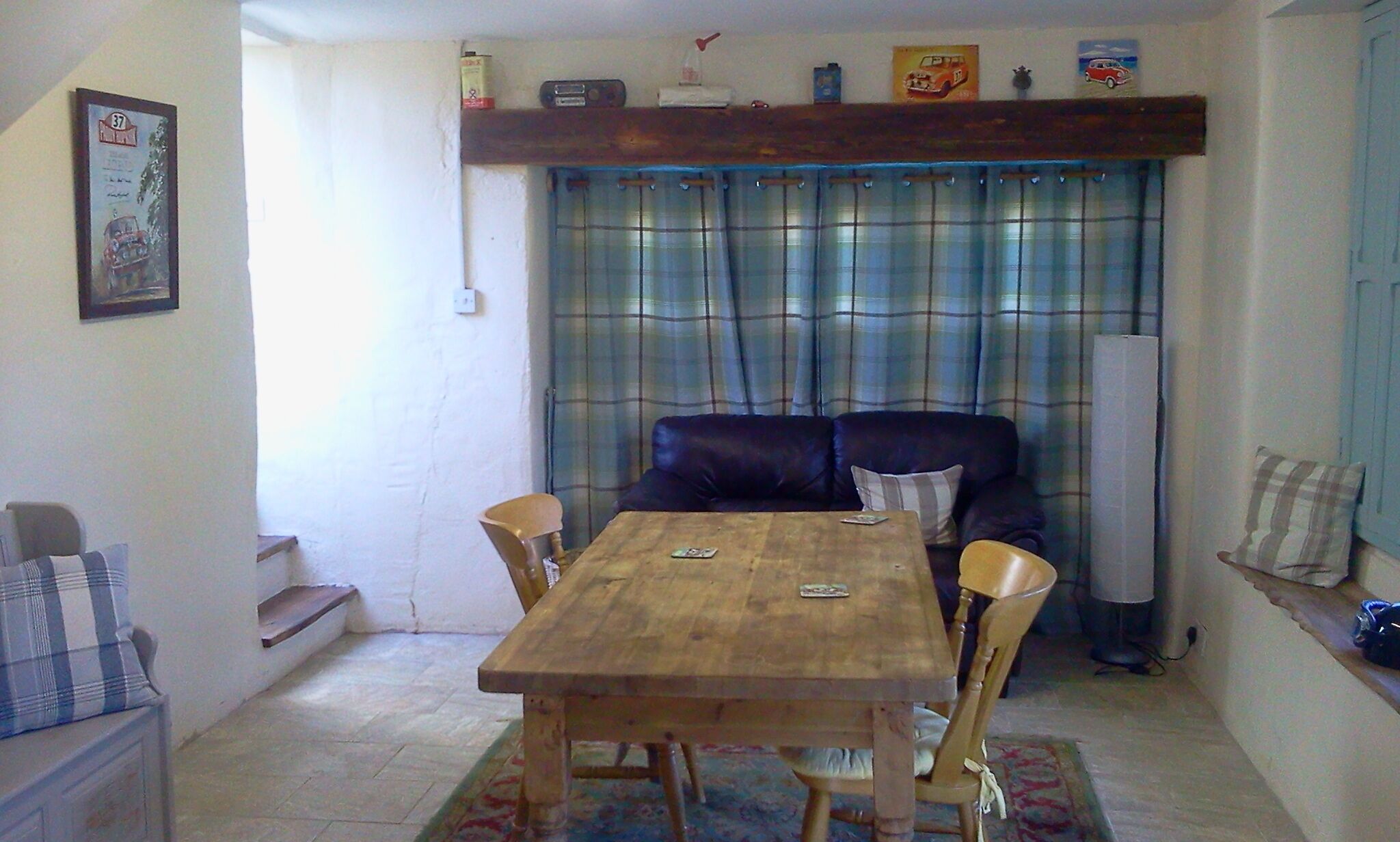 A dining area with a wooden table and chairs, a sofa, and a plaid curtain.