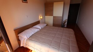 Un dormitorio con cama, mesita de noche, lámpara de pared y una puerta.