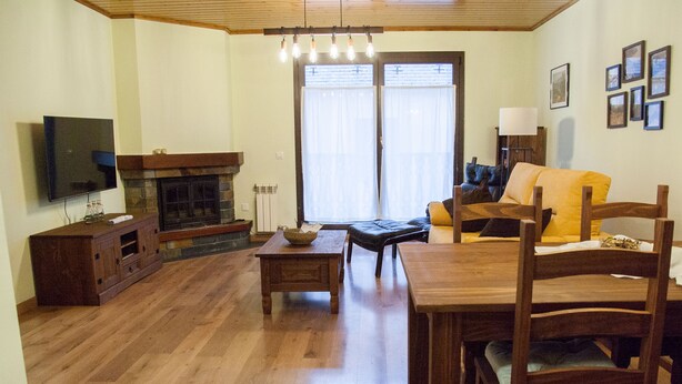 Un salon avec une cheminée, des meubles en bois, un téléviseur et un coin repas.