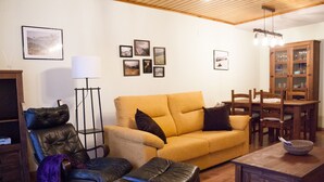 Un salon comprenant un canapé, un fauteuil, un pouf, une table basse en bois et un meuble.