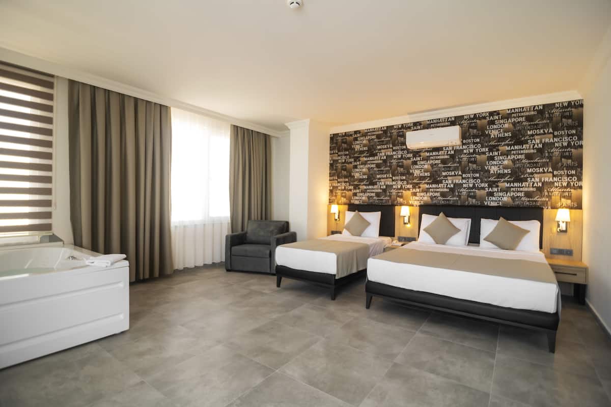 A hotel room with two beds, a sofa, a bathtub, and a wall with city names.