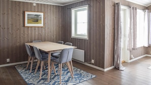 A dining area with a wooden table and chairs, a patterned rug, a framed picture on the wall, and a window with curtains. - 3 bedroom amazing home in Jaren (Jaren)