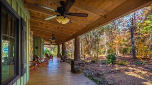 A wooden deck with ceiling fans, stone pillars, and outdoor seating.