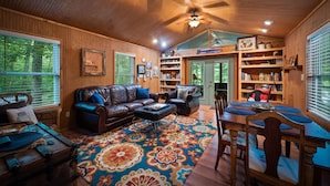 A cozy living room with a large wooden ceiling, leather sofas, a coffee table, and a vibrant rug. - Owl’s Perch-lakefront, paddle boards, pool table (Mentone)