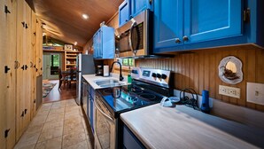 A modern kitchen with blue cabinets, a stainless steel stove, and a wooden ceiling. - Owl’s Perch-lakefront, paddle boards, pool table (Mentone)