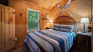 A wooden-paneled bedroom with a bed, two wall-mounted lamps, a window with blinds, and a ceiling fan. - Owl’s Perch-lakefront, paddle boards, pool table (Mentone)