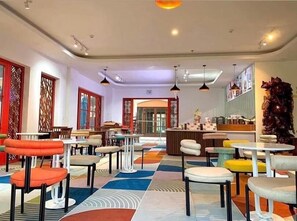 A restaurant with multiple tables and chairs, a patterned floor, and a counter with food items. - Harry Phu Quoc 1 (Phu Quoc)