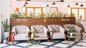 Un área de recepción con un mostrador de madera, tres sillones tapizados y un suelo de baldosas blanco y negro.