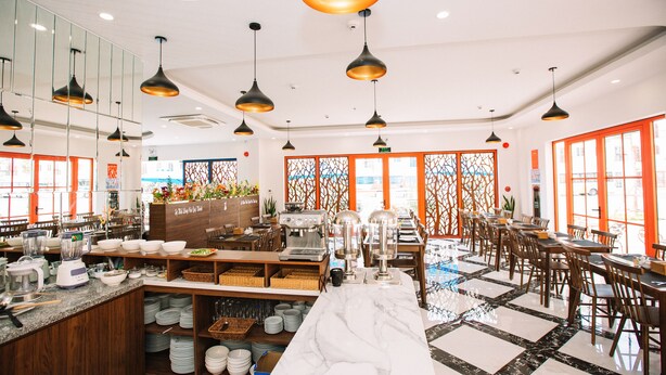 Un restaurante moderno con mostrador de mármol, sillas de madera e iluminación colgante.