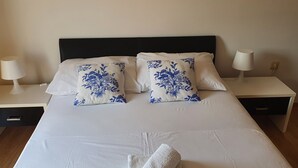 A neatly made bed with white bedding and two decorative pillows with blue floral patterns.