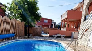 Une piscine bordée de pierres, entourée d’une clôture en bois et d’une terrasse en pierre.