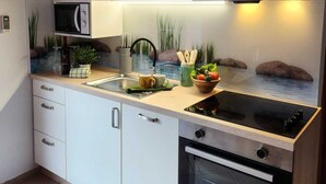 Une cuisine moderne avec des meubles blancs, un four à micro-ondes encastré, une cuisinière à gaz et un grand four.