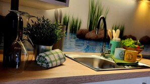 Une cuisine moderne équipée d’un four à micro-ondes encastré, d’un évier et d’un plan de travail agrémenté d’une plante en pot et d’une bouteille de vin.