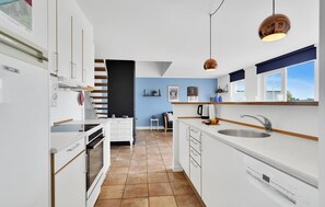 Enjoy cooking in this well-equipped kitchen with a central island, stainless steel sink, oven, and range hood.