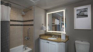 A bathroom with a bathtub, a shower with a grab bar, a sink with a mirror, and a toilet. - Oceanfront Villa at Grand Dunes (Myrtle Beach)