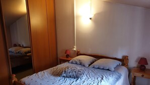 Et soveværelse med en træseng, et natbord med lampe, et spejl og en lampe fastgjort til væggen.