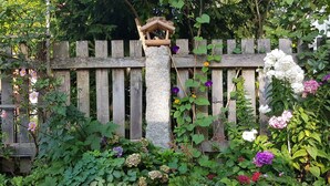 A garden with a wooden fence, a stone pillar, and various flowering plants. - Stylishly furnished vacation apartment in Dresden including bicycles, close to the city center (Dresden)