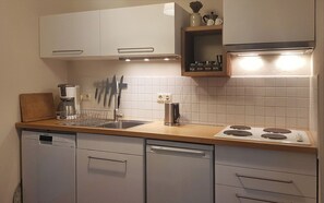 Compact kitchen with a sink, coffee maker, stove, and dishwasher.