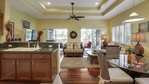 A spacious kitchen with a central island, wooden cabinets, and a dining area with wicker furniture. - Beautiful Condo with a Tree House Feel (Port St. Lucie)