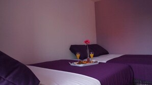A hotel room with two beds, purple bedding, a tray with breakfast, and a flower on the nightstand. - Modern Studio A4 for 2-3 people with 2 swimming pools (Pag)