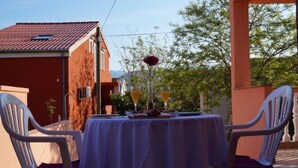 An outdoor dining area with a table set for two, surrounded by white plastic chairs. - Modern Studio A4 for 2-3 people with 2 swimming pools (Pag)