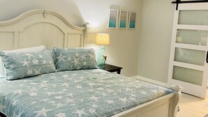 Un dormitorio con cama, mesita de noche, lámpara y decoración en la pared.