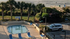 Zona de piscina con sillones de descanso, vista a la playa y señal de salvavidas.
