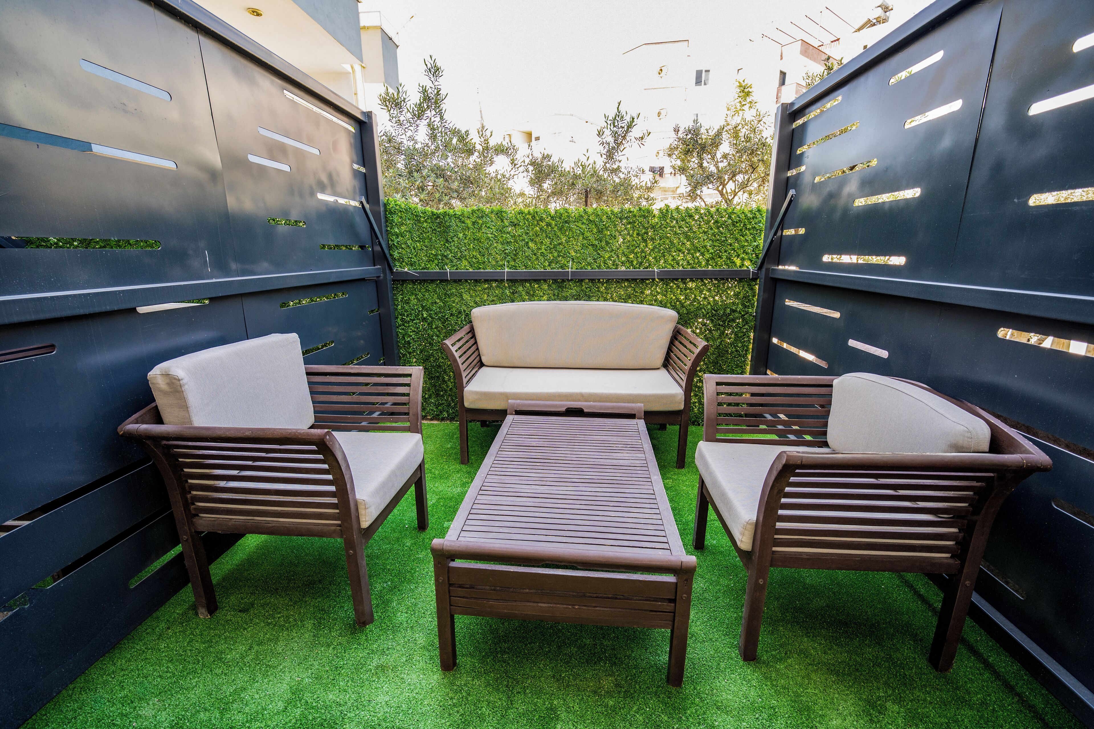 A patio with a sofa, two chairs, and a table.