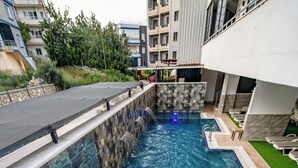 A swimming pool with a slide, surrounded by a modern building with balconies. - Club Efes Otel (Silifke)