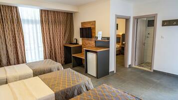 Ein Hotelzimmer mit zwei Betten, einem Schreibtisch, einer Dusche und Blick auf die Stadt.