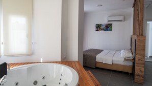 A modern bathroom with a wooden vanity, a bathtub, and a small bed. - Club Efes Otel (Silifke)