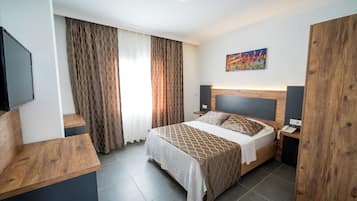 Ett modernt hotellrum med en säng, sängbord i trä, en platt-TV och en tavla på väggen.