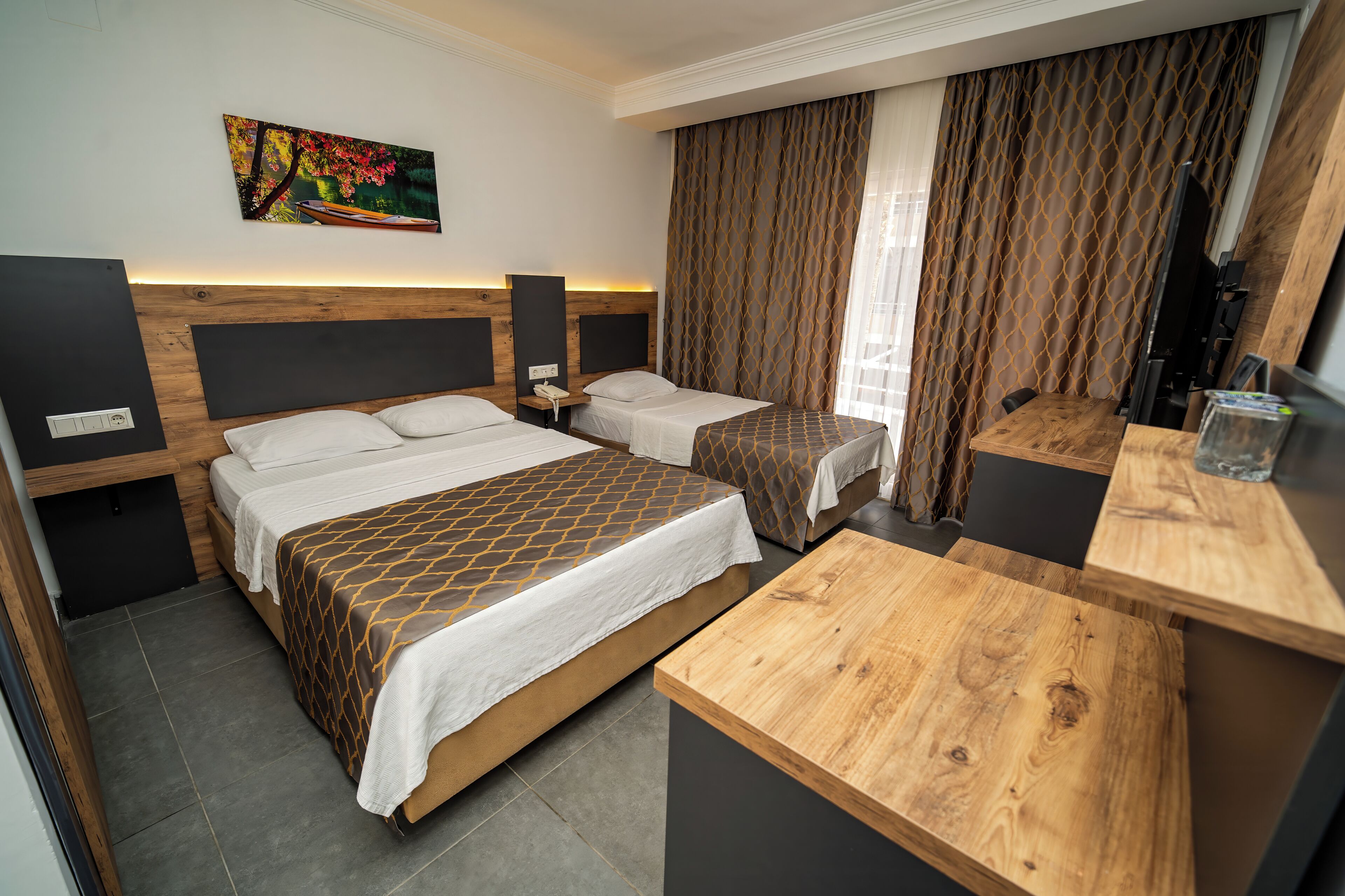 A hotel room with two beds, a wooden desk, a TV, and a painting on the wall.